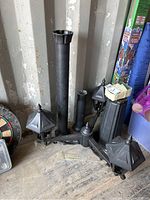 Disassembled outdoor light post components including three lantern light fixtures, two pole sections, and base grouped on a floor.