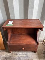 Front view of the wooden nightstand showing the drawer, open shelf, and top surface.
