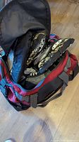 Photo showing red and black sports bag with two pairs of ice hockey skates, partially visible inside the bag.