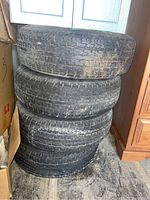 Stack of four used trailer tires showing tread pattern and wear.