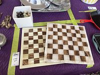 Two heavy stone chess boards side by side with a container of chess pieces