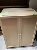 Front view of IKEA Oxberg two-door cabinet, closed doors show light wood finish with wooden knobs.
