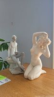 Photo showing both sculptures side by side on a wooden surface under natural light.