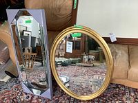 Two wall mirrors shown: one rectangular beveled mirror in original box, one gilt oval beveled mirror.