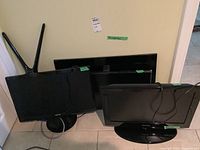 Four computer monitors positioned upright on floor, showing front screens and stands with cables attached to some units.