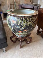 Front and side view showing the large ceramic planter on the wooden stand in a garage setting.
