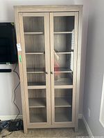 Front view of the 6 tiered bookshelf with two glass panel cabinet doors, showing interior shelves and round knobs on doors.