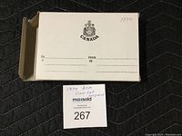 Photo of the outer shipping box with Canada crest, unopened inner box with gold border, and the unopened beige and gold bordered inner box housing the coins.