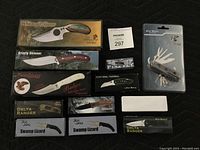 Photo showing all 12 boxed cutting utensils including Grizzly Skinner, Badger, Delta Ranger, Swamp Lizard, Fire Fly, Navy Seal Tactical, Hurricane Knife and a multi-function cutting tool.
