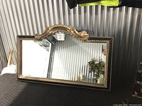 Front view of the rectangular Ren-Wil mirror showing the ornate brown and gold/bronze molded trim and decorative crest on top.