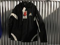 Front view of men's black NBC Sports winter coat with attached tags, showing logo and reflective accents.
