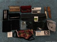 Full lot overview showing pen and pencil sets, watch, divot repair tool, magnifier and other items