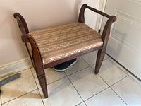 Upholstered bench with wooden frame, showing curved armrests and striped floral seat fabric.