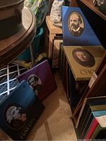 Photo showing multiple classical record album sets with portraits of famous composers such as Haydn, Chopin, Liszt, and Kodaly inside shelves and near floor in basement.