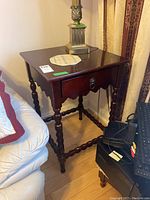 Front and side view of wooden end table showing the top surface, drawer, and twisted legs.