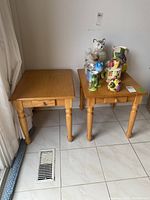 Pair of wooden end tables side by side on tiled floor, one with decorative items on top, showing overall size and color.