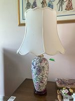 Front view of ceramic table lamp showing floral design on base and scalloped white fabric shade