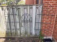 Three trellis panels leaning against fence: two large and one small decorative panel visible