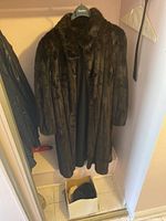 Full front view of full-length dark brown mink fur coat hanging on hanger