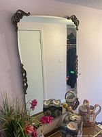 Large rectangular wall mirror with ornate decorative corners mounted on wall, reflective surface visible, measuring 49x31