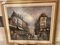 Framed oil painting on canvas depicting a street scene with buildings and people walking, showing overall view of the artwork and frame.