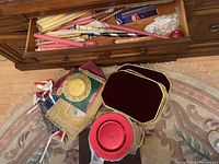 Photo of placemats, red plastic chargers, and gift bags on a rug near a wooden dresser drawer.
