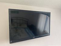 Front view of Haier 32 inch television showing screen and bezel with Haier logo. Screen is off, reflecting surrounding room.