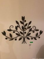 Front view of metal wall sculpture showing branches, leaves, and flower details
