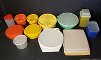 All 12 vintage Tupperware containers shown in various sizes and colors including orange, yellow, white, green, blue, and gray, arranged for viewing.