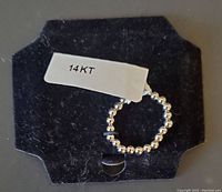 White gold ring composed of round beads on a black card backing with '14KT' label