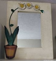 Full view of the mirror with 3D metal flower pot decoration showing three flowers and green leaves.