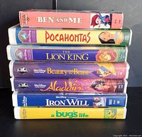 Stacked view of 7 Disney VHS tapes showing spine titles and artwork: Ben and Me Mini Classic, Pocahontas, The Lion King, Beauty and the Beast, Aladdin, Iron Will, A Bug's Life.