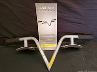 Lo-Bak Trax spinal back stretcher with the instruction manual placed on a black fabric background, showing front view of the device with soft handles and metal support plates.