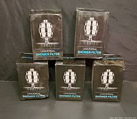Lot of 5 boxed universal shower filters arranged in two rows, four in front and one behind.