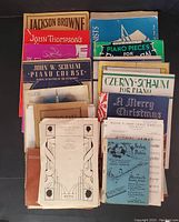 Top view of the vintage sheet music and piano music books, showing a variety of colorful covers and titles including John W. Schaum and Jackson Browne.