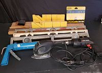 Full view of the tool lot showing all items including Black & Decker corded drill, palm sander, three 24 inch levels, yellow plastic miter box, caulking tool, paint brushes, and screwdriver holder.