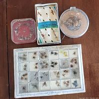 Four separate assortments of vintage fishing flies displayed in original plastic compartment boxes and containers, including Wright & McGill, Orvis, and Western brands.
