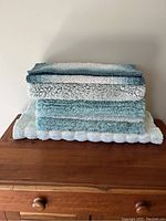 Stack of four bathroom mats showing different sizes and the blue-to-cream gradient color scheme.
