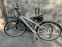 Side view of silver Fuji Cross 3.0 hybrid bike leaning against garage door