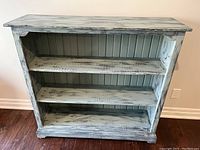 Front view of the pine bookcase showing three shelves and distressed chalk paint finish.