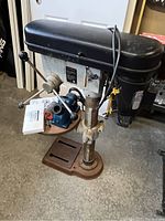 Side angled view of Rexon 14 drill press and Drill Doctor sharpener on work table.