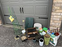 Photo of entire lot showing various gardening items including green metal tomato cages, bird feeders, pots, and gardening materials
