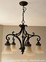 Full view of the 5-light chandelier hanging from ceiling showing the metal frame and bell-shaped glass shades.