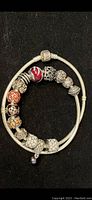 Full view of Pandora silver snake chain necklace with various charms on black background.