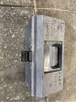 Closed gray plastic toolbox with black latch and handle, shown from top view on stone floor.