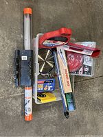 Overview photo showing taper jig, dado jig kit, multiple table saw blades, and dual track guide system packed in plastic bin on cement floor.