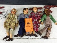 Photo showing four Hazelle's Marionettes laid out, two female and two male with visible clothing and ferry airplane control bars attached.