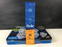 Photo of Magnetix 3D magnetic construction set in tin box with a blue 3Doodler box standing upright on top, displaying product and lot items