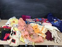 Full view of multiple scarves and gloves laid out on a table showing variety in color and style