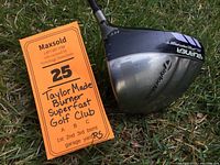 Photo of TaylorMade Burner Superfast driver clubhead showing branding and used condition on grass background.